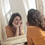 A woman looking at the mirror and smiling