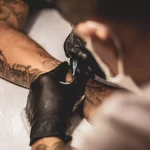 Tattoo artist with tattoo gun drawing a tattoo